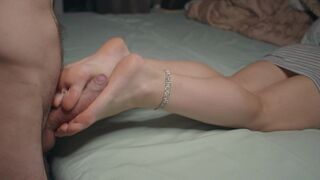 A petite beauty shows her feet and does a footjob, finishing with cum on her soles