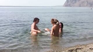 Three naked beauties on the coast, enjoying the wind and the sea