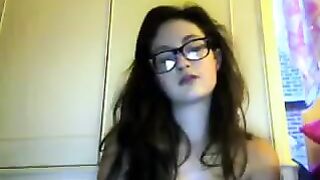 A cute girl in glasses takes off her clothes during the video chat