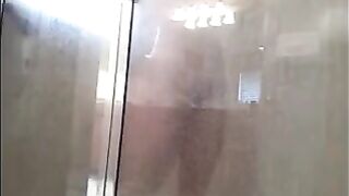 A guy washes his body in the shower, unaware of being watched