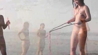 A naked girl is having fun on the beach with her companion