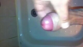 The kid masturbates his dick under the jet of water in the shower