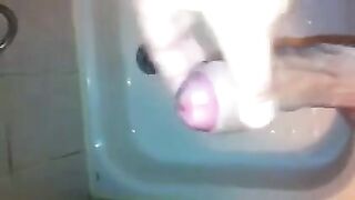 The kid masturbates his dick under the jet of water in the shower