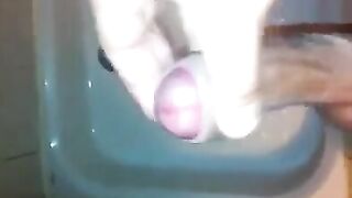 The kid masturbates his dick under the jet of water in the shower