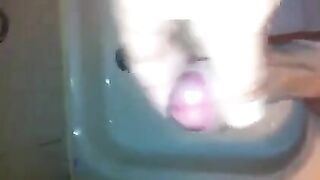 The kid masturbates his dick under the jet of water in the shower