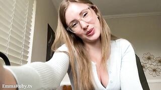 A girl with glasses puts on lipstick and caresses herself on the bed